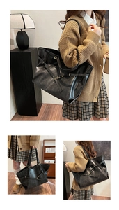 Detail view of large black leather tote bag featuring crisscross straps and metal buckles