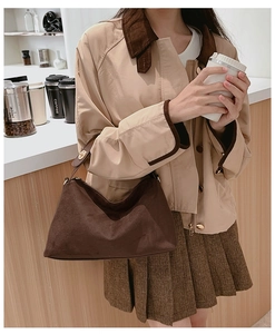 Detail of dark brown matte suede shoulder bag with gold hardware and leather strap