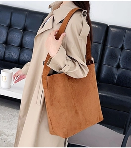 Detail of soft brown suede texture and wide shoulder strap on a large tote bag