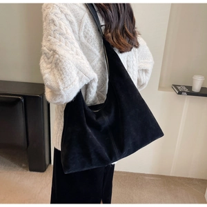Détail d'un grand sac cabas en daim noir avec finition mate et bandoulière intégrée