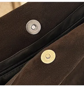 Détail des boucles magnétiques en argent et du zip sur le sac fourre-tout en daim marron