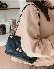 Close-up of quilted black crossbody bag with golden chain strap and swivel lock buckle