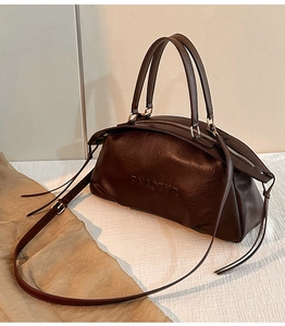 Gros plan du sac Boston marron foncé avec texture huilée vintage et logo en relief