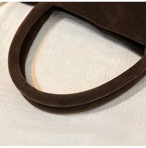 Détail des poignées rondes durables d'un sac cabas en daim marron pour femme