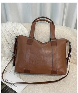 Detailed close-up of brown faux leather texture and cross-stitched handles on stylish bag