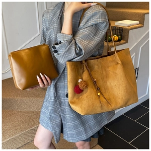 Detail view of mustard yellow suede tote bag with decorative tassel and inner pouch