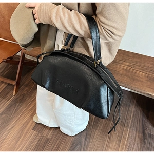 Gros plan sur le sac bowling noir texture litchi avec lettrage embossé et fermeture