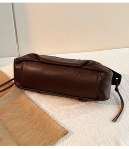 Détail de la base du sac en similicuir marron foncé avec cordons et coutures soignées