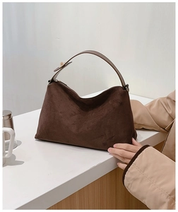 Close-up of soft brown suede crescent bag with wide leather strap and vintage texture