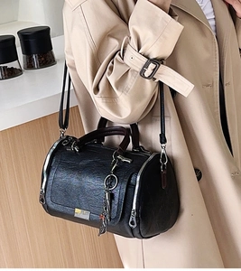 Elegante borsa Boston nera con trama in pelle retrò indossata da una modella in interni