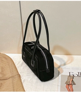 Macro detail of black suede shoulder bag featuring contrast white stitching and silver zipper