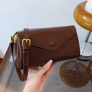 Minimalist brown crossbody bag with envelope flap and adjustable gold-buckle strap