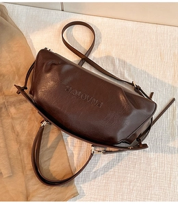Détail d'un sac à main en cuir marron foncé montrant la texture et les boucles dorées