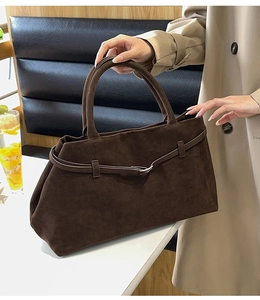 Détail d'un cabas mat marron foncé avec fine sangle à boucle dans un cadre de café chic