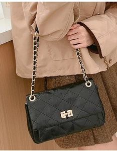 Detail of classic black quilted leather bag with gold chain strap and twist lock