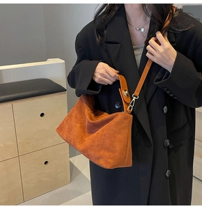 Detail of soft orange-brown matte handbag with dark leather strap and gold hardware accents