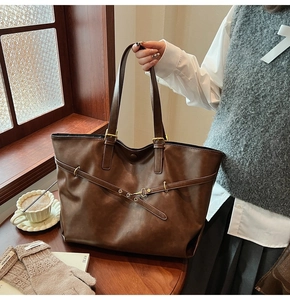 Detail of a large vintage brown tote bag with decorative buckle strap and gold hardware