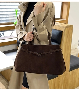 Détail du sac cabas en daim marron foncé avec boucle décorative et texture dépolie