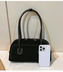 Detail view of black matte shoulder bag featuring white contrast stitching and dual zippers