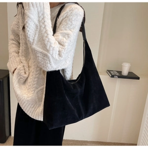 Grand sac cabas minimaliste en daim noir porté à l'épaule dans un style de vie élégant