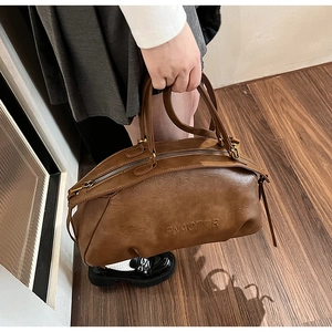 Détail du sac bowling en cuir marron vintage avec logo cœur gaufré et doubles anses