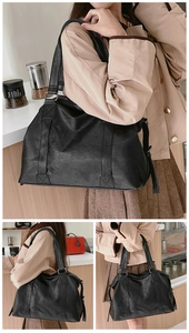Detail view of large black leather tote bag featuring durable reinforced stitching