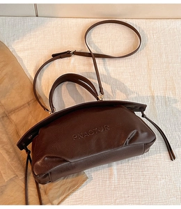 Détail du sac cabas marron foncé montrant le logo embossé et les bandoulières en cuir