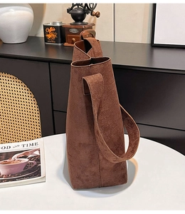 Close-up of deep brown suede tote bag showing premium matte texture and wide shoulder strap