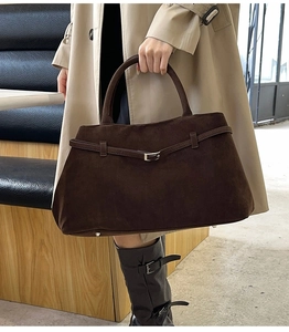 Gros plan détaillé d'un sac cabas en daim marron foncé avec clous métalliques et texture