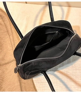 Close-up of black suede tote interior showing white contrast stitching and silver zipper