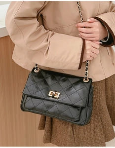 Close-up of black quilted leather crossbody bag with gold chain and turn-lock detail