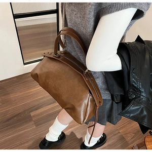 Détail de la texture du cuir marron et du logo embossé sur ce sac à main vintage