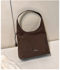 Dettaglio ravvicinato della borsa tote in pelle scamosciata marrone con testo stampato