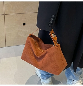 Detail of caramel suede handbag with gold zipper and unique twist lock handle detail