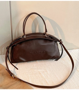 Détail de la texture en cuir PU café foncé avec logo embossé et zip doré brillant
