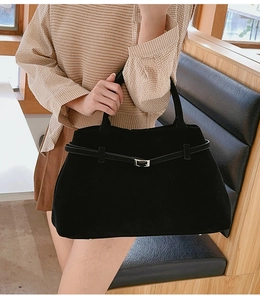 Détail d'un grand sac cabas noir mat avec une boucle en métal argenté et une sangle décorative