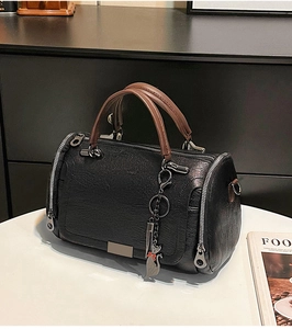 Dettaglio borsa Boston in pelle nera martellata con ciondolo a gatto e zip in metallo