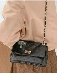 Detailed view of the quilted texture and golden metal twist lock on the black chain bag