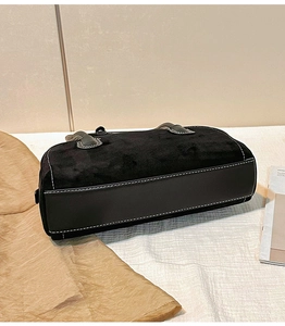 Detail showing suede and leather contrast stitching on black minimalist shoulder bag