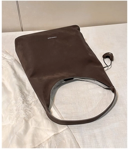 Dettaglio della borsa tote scamosciata marrone scuro con texture e scritte moda
