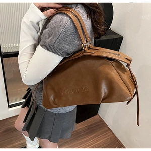 Détail du sac PNAOTOR en cuir marron avec logo embossé et pampille de fermeture