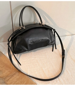 Détail du sac à main en cuir noir avec logo embossé et finitions métalliques dorées