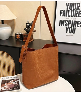 Detail view of brown suede tote bag with thick shoulder strap and square buckle buckle decor