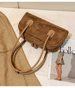 Detailed macro view of brown suede shoulder bag showing fine stitching and smooth zippers