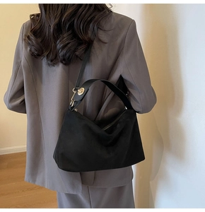 Detail of vintage matte black crossbody bag with gold clasp and wide leather handle
