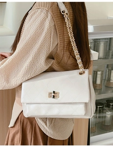 Close-up of white quilted chain bag with gold hardware and elegant leather strap texture