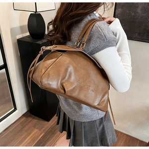 Détail du sac à bandoulière en cuir marron texturé avec anneaux de connexion en métal