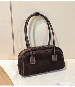 Macro detail of brown suede shoulder bag featuring contrast stitching and sturdy long handles