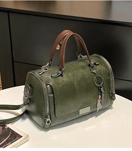 Dettaglio della borsa Boston verde scuro con manici marroni e pelle vintage
