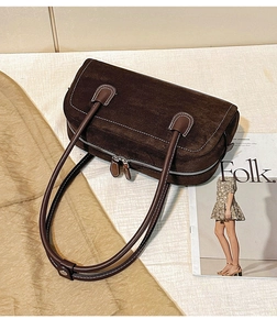 Detailed close-up of dark brown suede shoulder bag featuring white contrast stitching and hardware